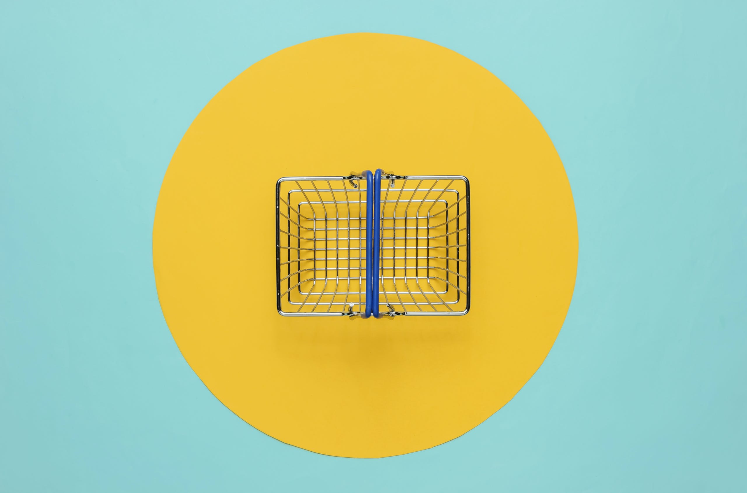Mini-shopping-basket-on-blue-background-with-yellow-circle-scaled